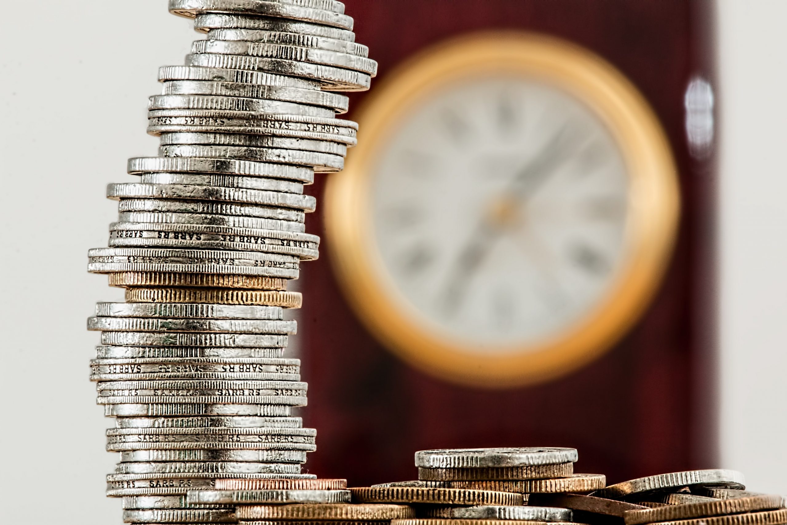 Stack of coins in front of a clock